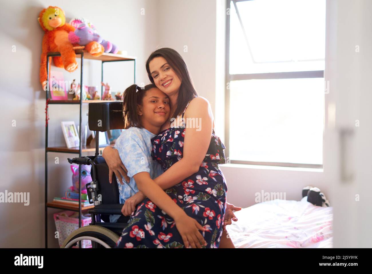 Portrait happy, affectionate mother hugging disabled daughter at home Stock Photo