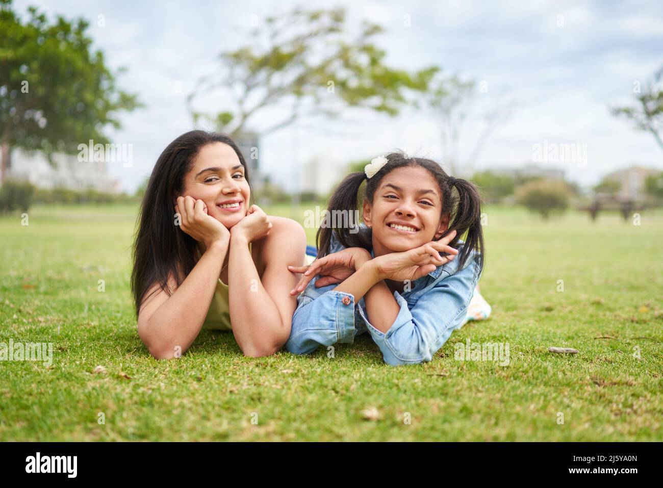 Portrait happy brunette mother and daughter laying in park grass Stock Photo