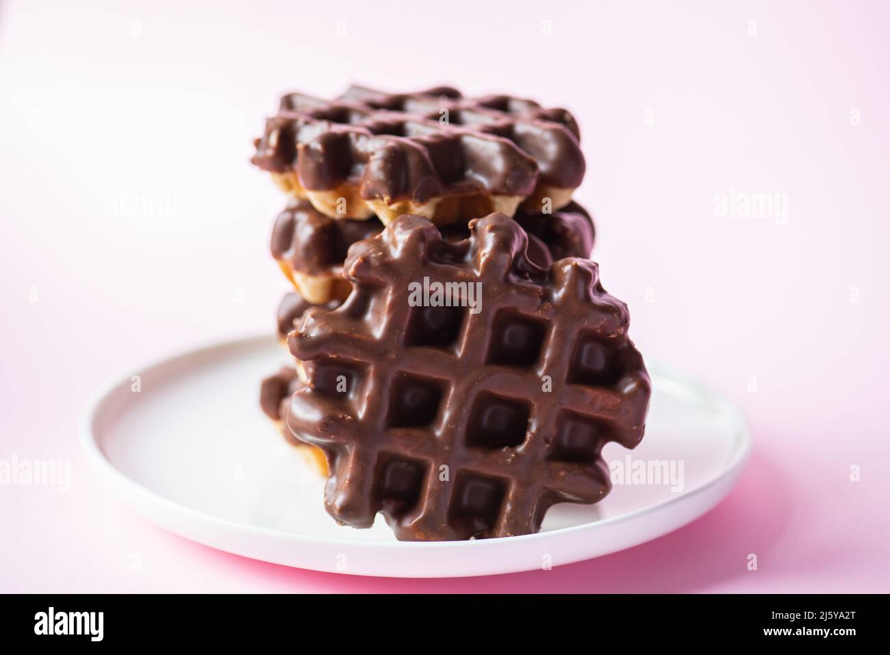 Stack of chocolate waffles. Close up and pink background. Stock Photo