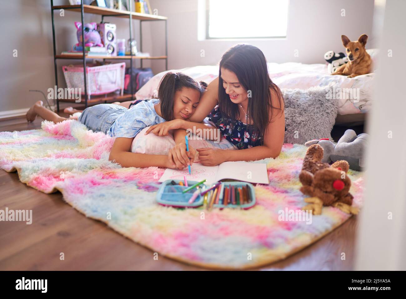Mother and daughter drawing on bedroom rug Stock Photo
