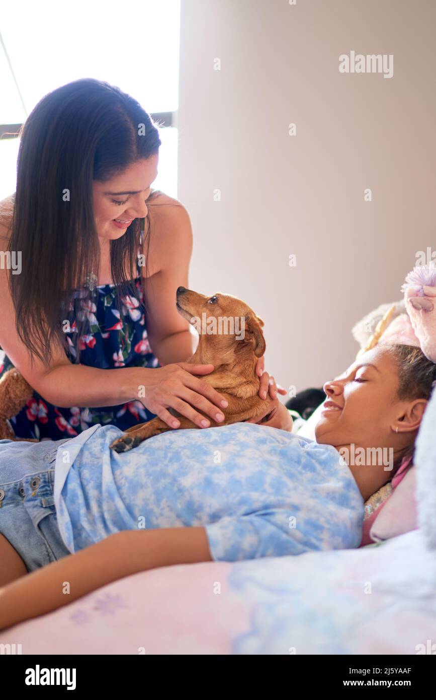 Mother, disabled daughter and cute dog cuddling on bed at home Stock Photo