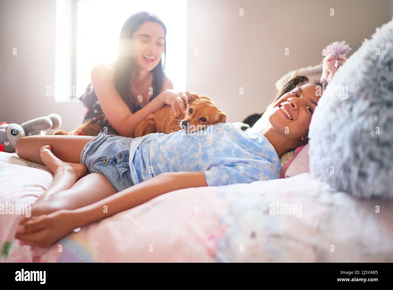 Portrait happy disabled girl laying on bed with dog and mother Stock Photo