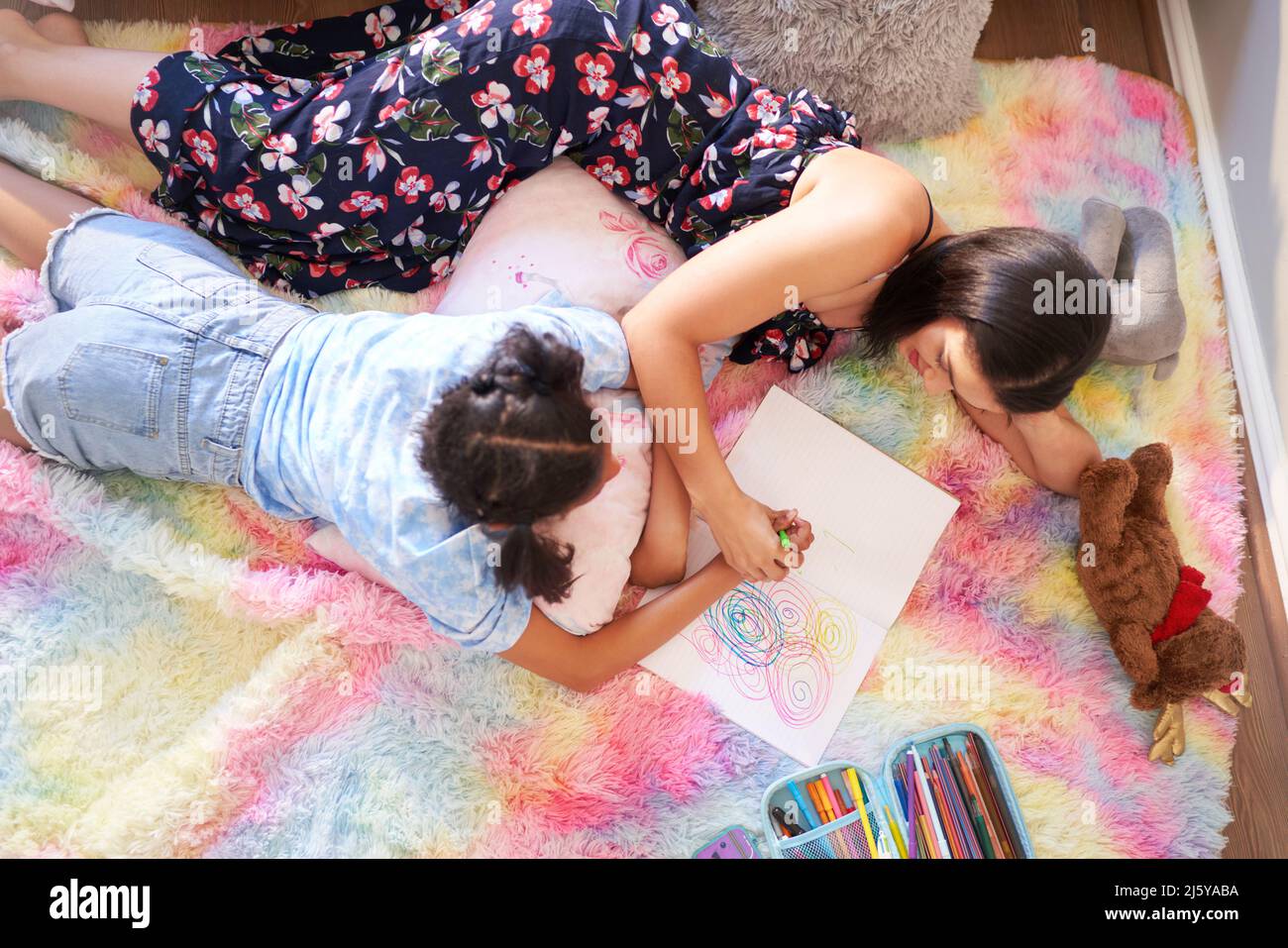 View from above mother and daughter drawing circles in notebook Stock Photo