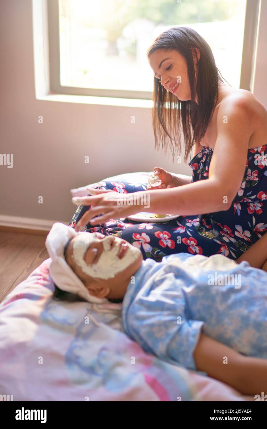 Mother giving daughter laying on bed a facial Stock Photo