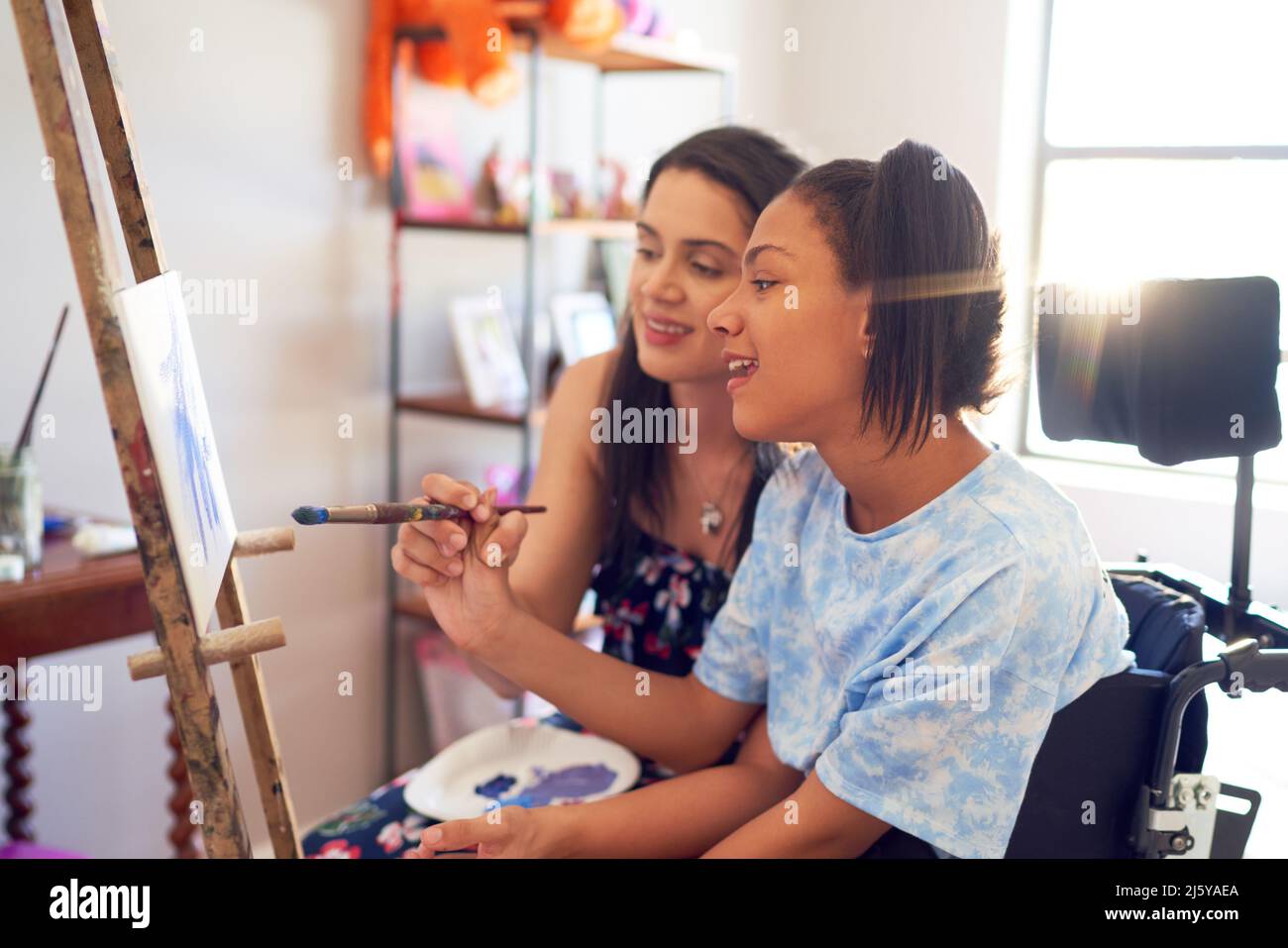 Mother and disabled daughter painting at easel in bedroom Stock Photo
