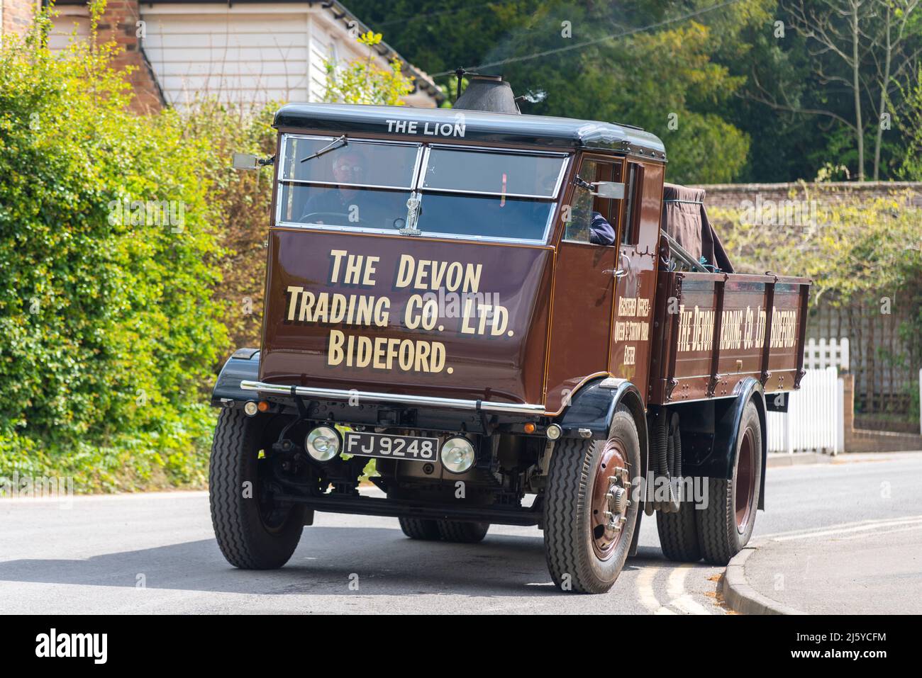 1933 Sentinel S4 Steam Waggon in a country road by cottages in Tenterden, Kent, UK. Preserved steam lorry named The Lion, in Devon Trading scheme Stock Photo