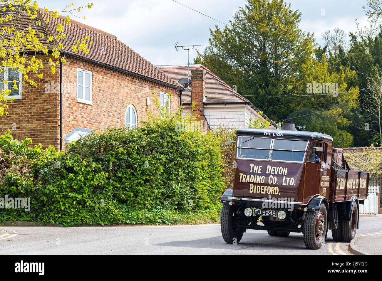 1933 Sentinel S4 Steam Waggon in a country road by cottages in Tenterden, Kent, UK. Preserved steam lorry named The Lion, in Devon Trading scheme Stock Photo