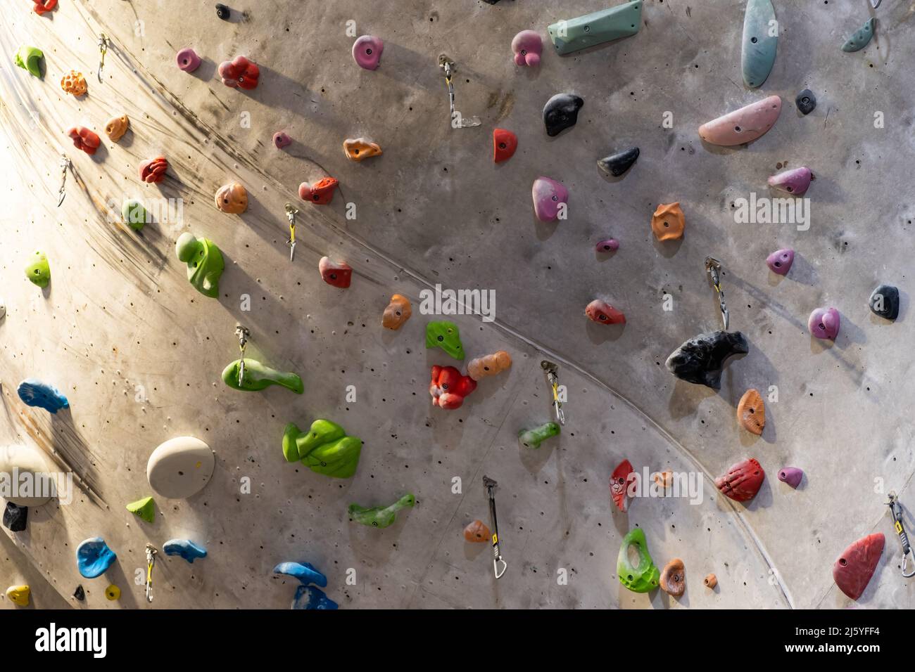 Artificial rock climbing wall with various colored grips Stock Photo