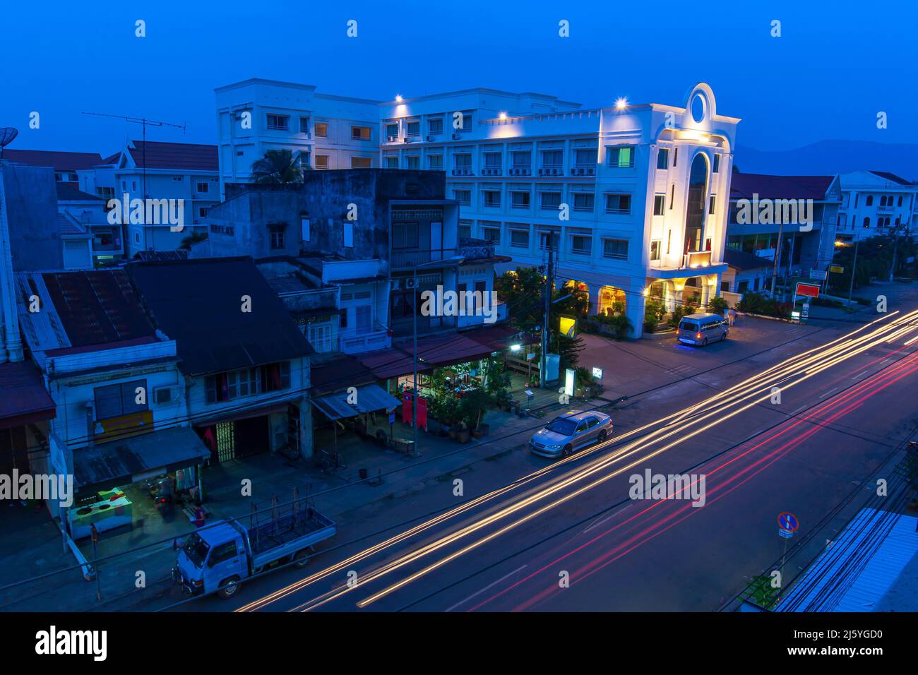High angle view of Pakse city at twilight, illuminated lights trails on the street, the old colonial hotel, and old residential buildings. Laos. Stock Photo