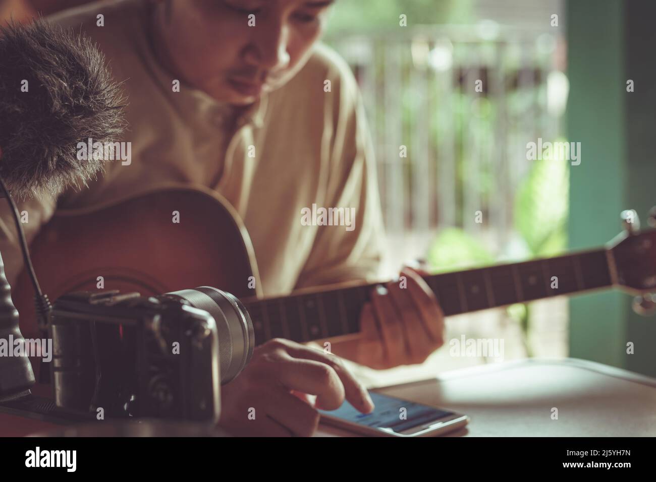 Young Asian man playing guitar relaxing in a cafe. Stock Photo