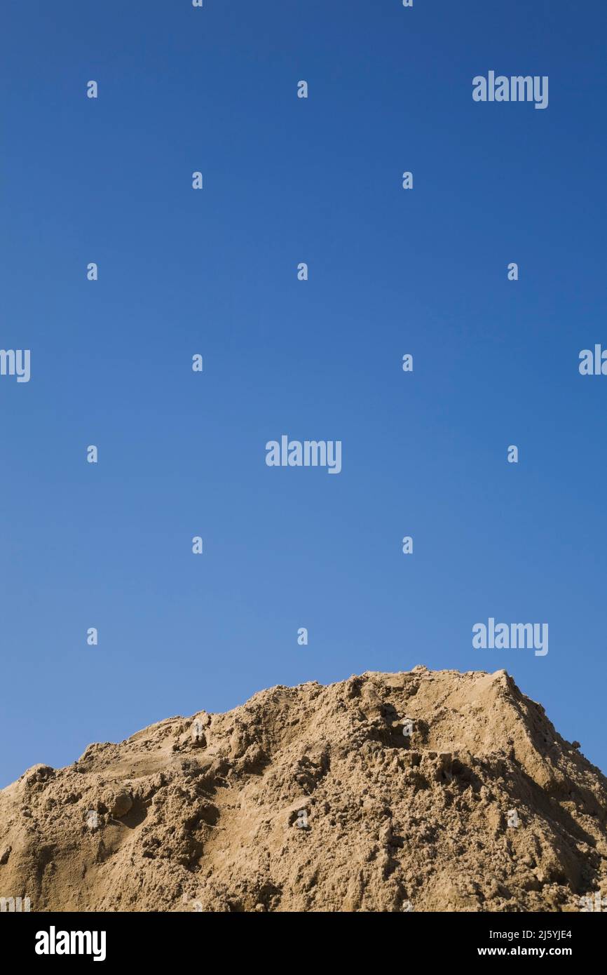 Close-up of a mound of fine sand against a blue sky background. Stock Photo
