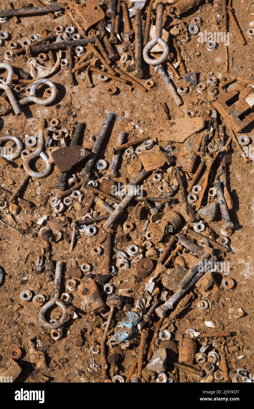 Closeup of assorted metal nuts and bolts on the ground at a scrap