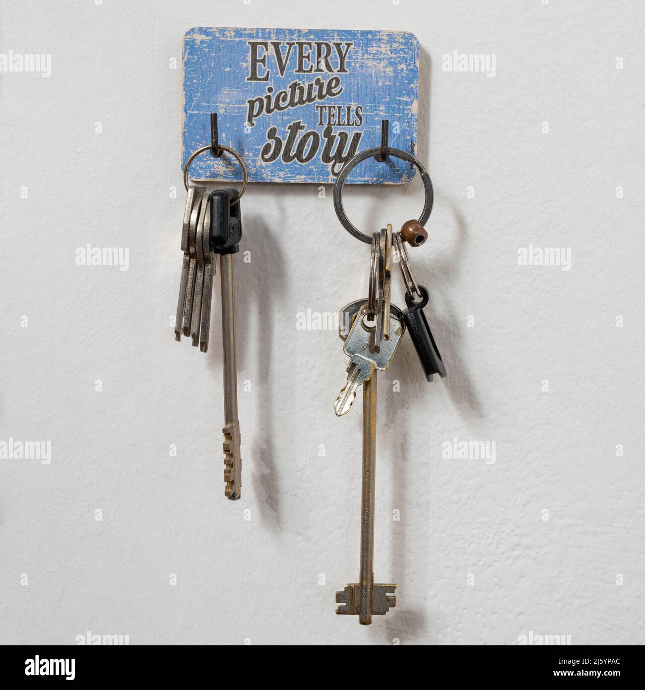 the words 'every picture tells a story' on a key ring hanging on the wall Stock Photo