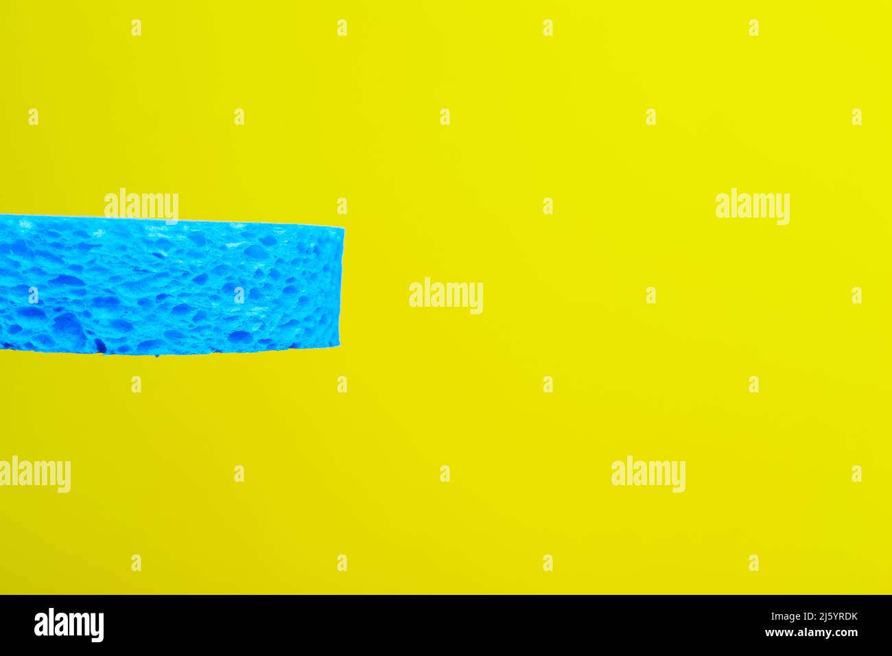 a blue sponge in front of a yellow background Stock Photo