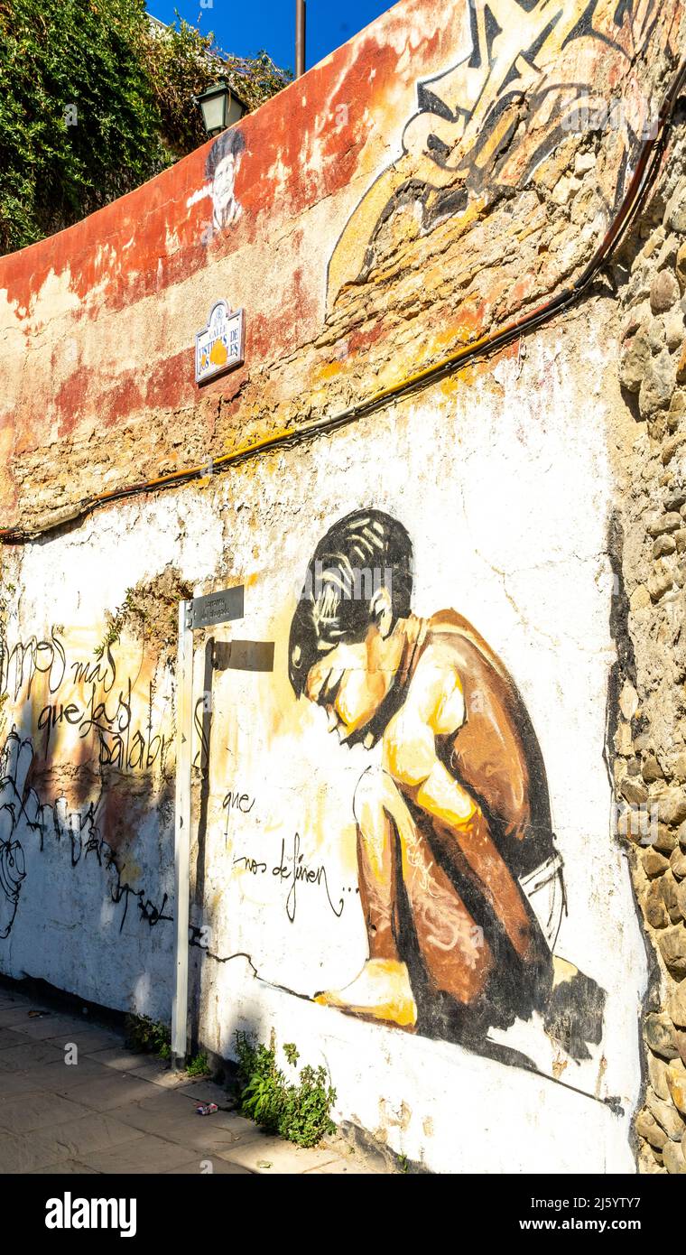 Squatting boy, street art mural by artist Raul Ruiz. Crouching child by Spanish muralist El Niño, Realejo, Granada, Andalucia, Spain Stock Photo