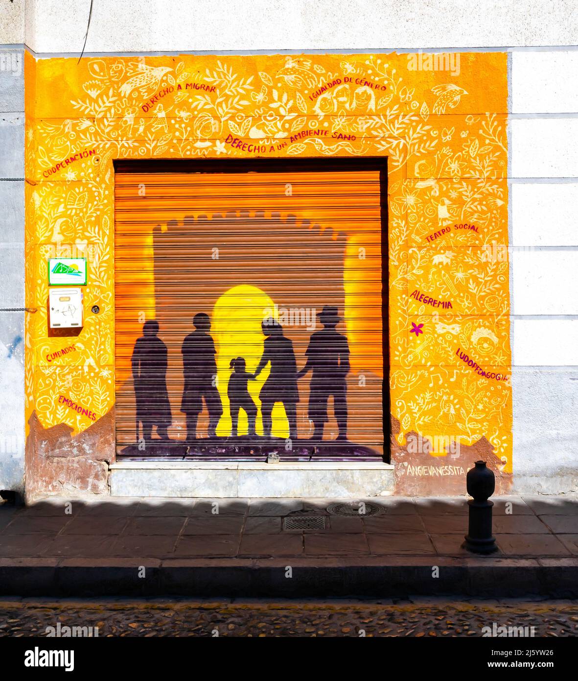 Mural on boarded door of ASPA - Asociacion Andaluza por la Solidaridad y la Paz, depicting silhoutte of family and the Sun. Granada, Spain Stock Photo