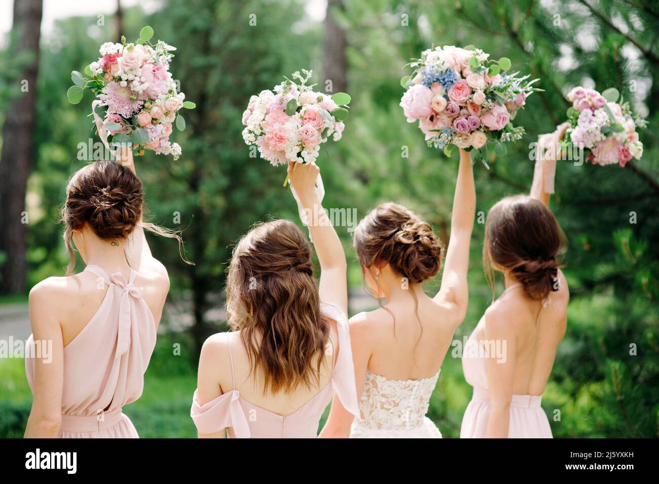 Bridesmaids in pink dresses and bride holding beautiful bouquets