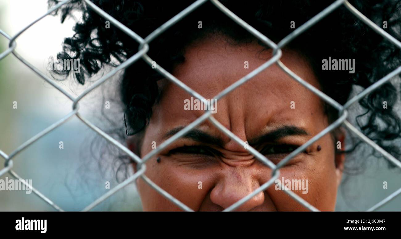 Angry upset african woman yelling seen through metal fence barrier ...