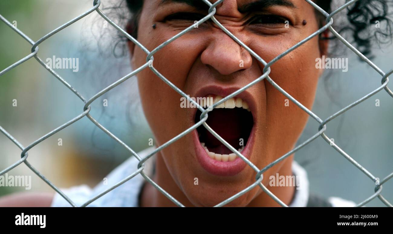 Angry upset african woman yelling seen through metal fence barrier ...