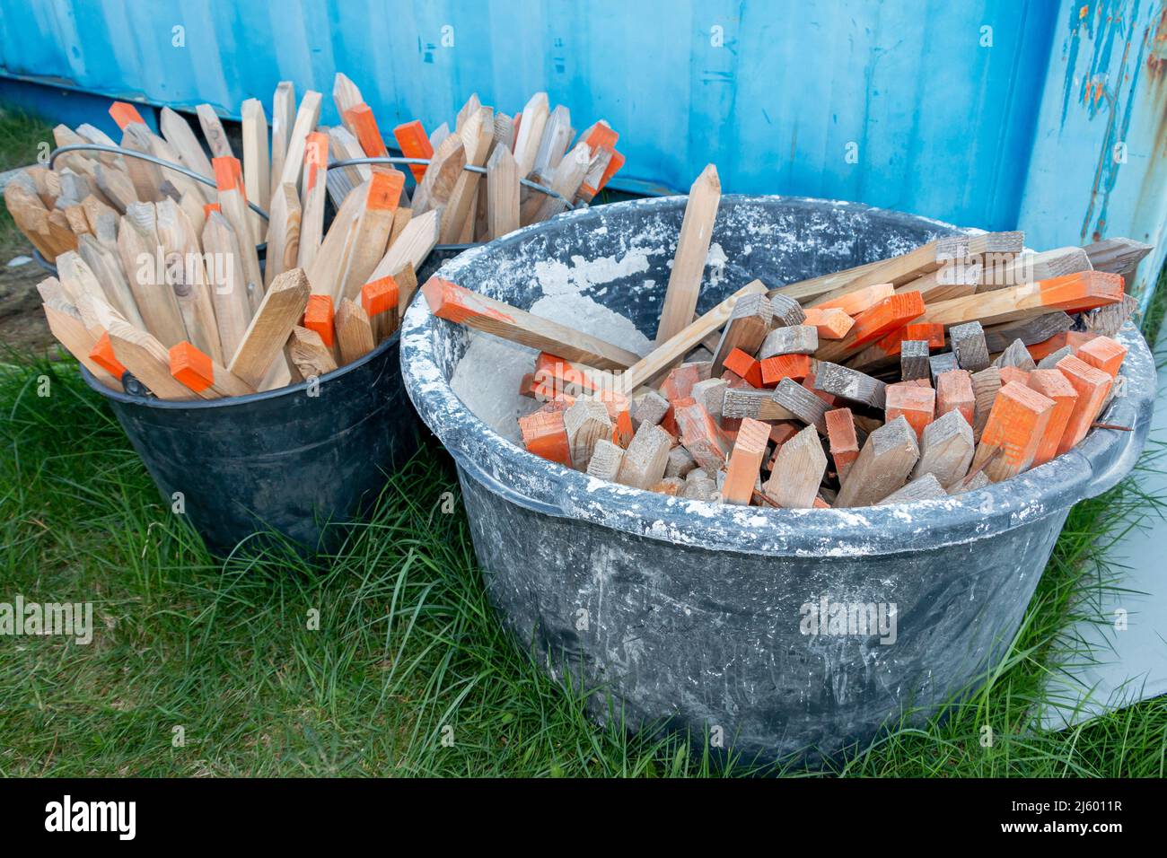 Wooden picket posts in plastic barrels, used for setting out and measuring a construction to be built Stock Photo
