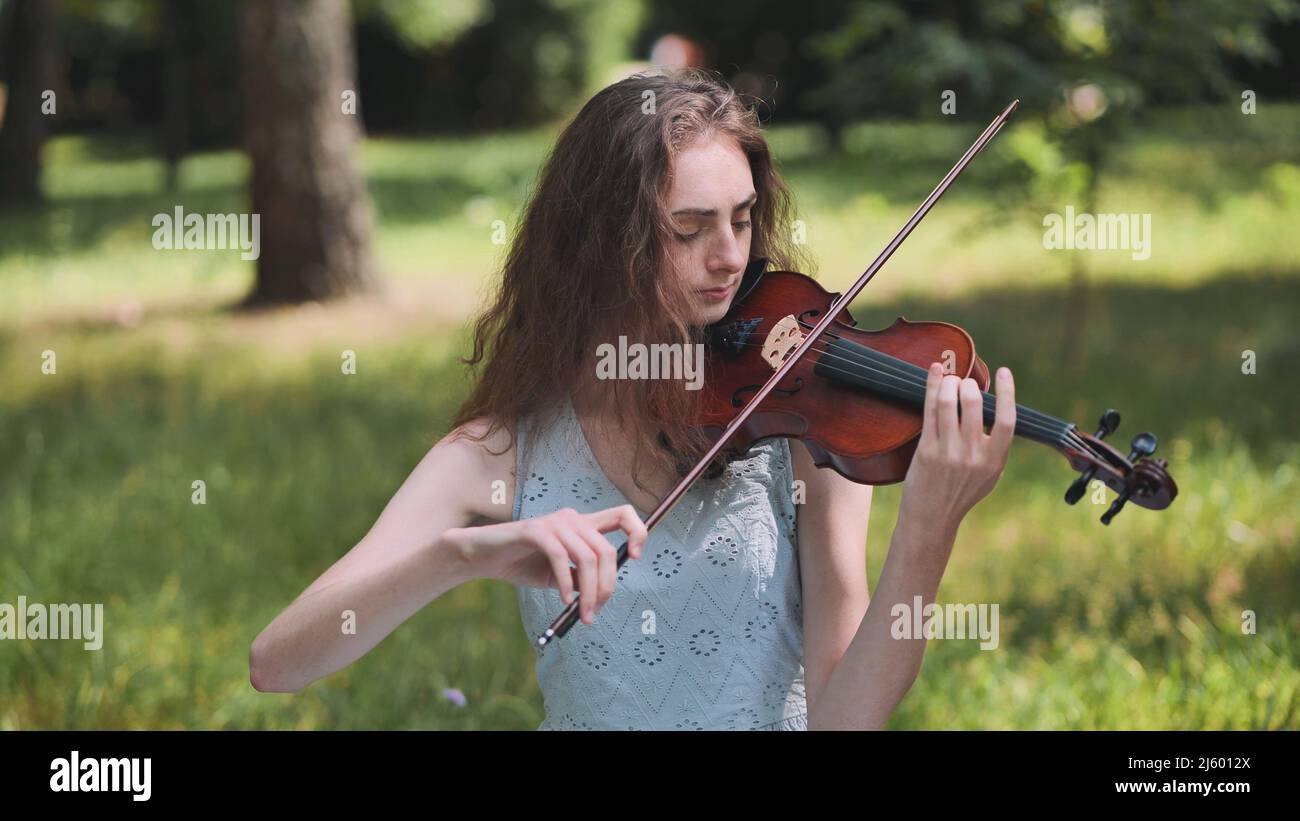 A young girl plays the violin in the city park Stock Photo - Alamy
