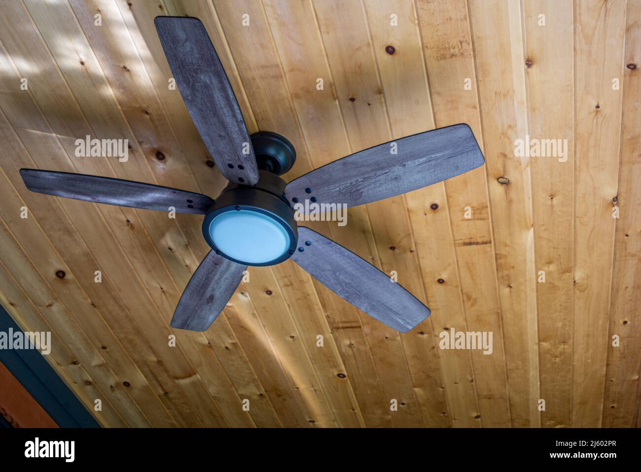 Wooden electric ceiling fan under a timbered ceiling Stock Photo