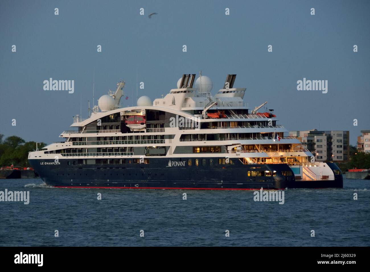 Ponant Cruises ship Le Champlain makes it's way down the river Thames at dusk after paying a port-call to London Stock Photo