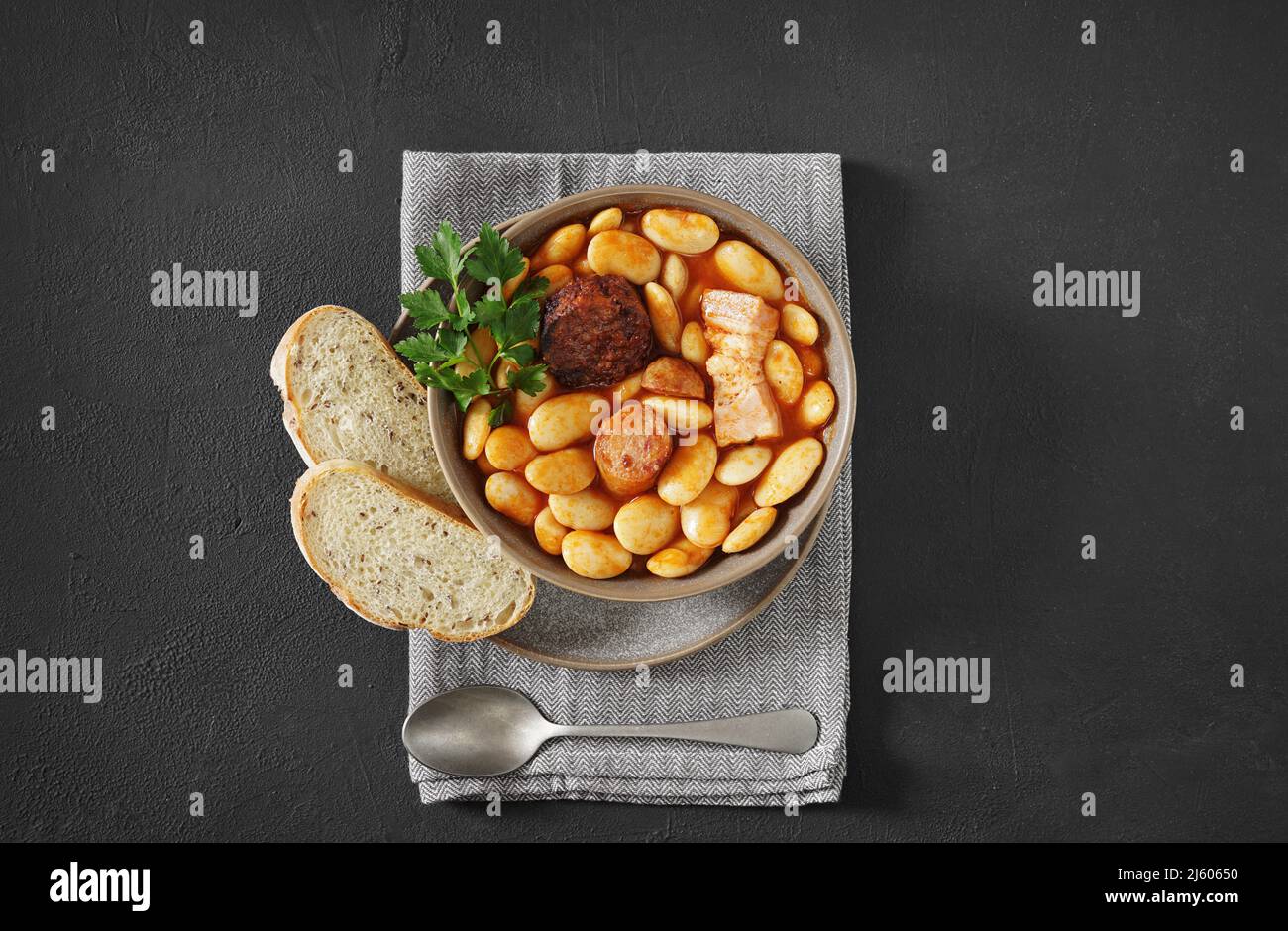Traditional recipe of beans with chorizo and blood sausage of Fabada Asturiana on a dark table. top view Stock Photo
