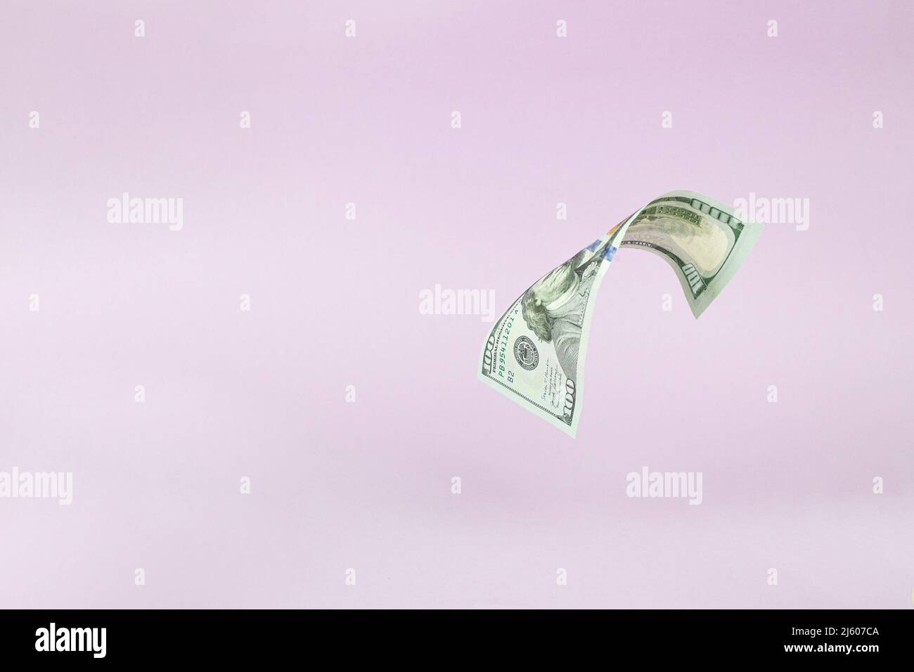 Flying 100 American dollars banknotes, on pink background. US 100 dollar bill close up. Flying money Stock Photo