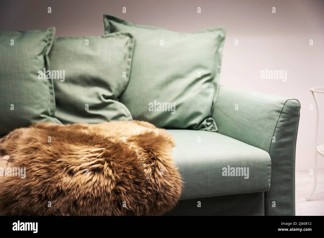 Light green sofa with pillows, plaid and fur cape, Living room