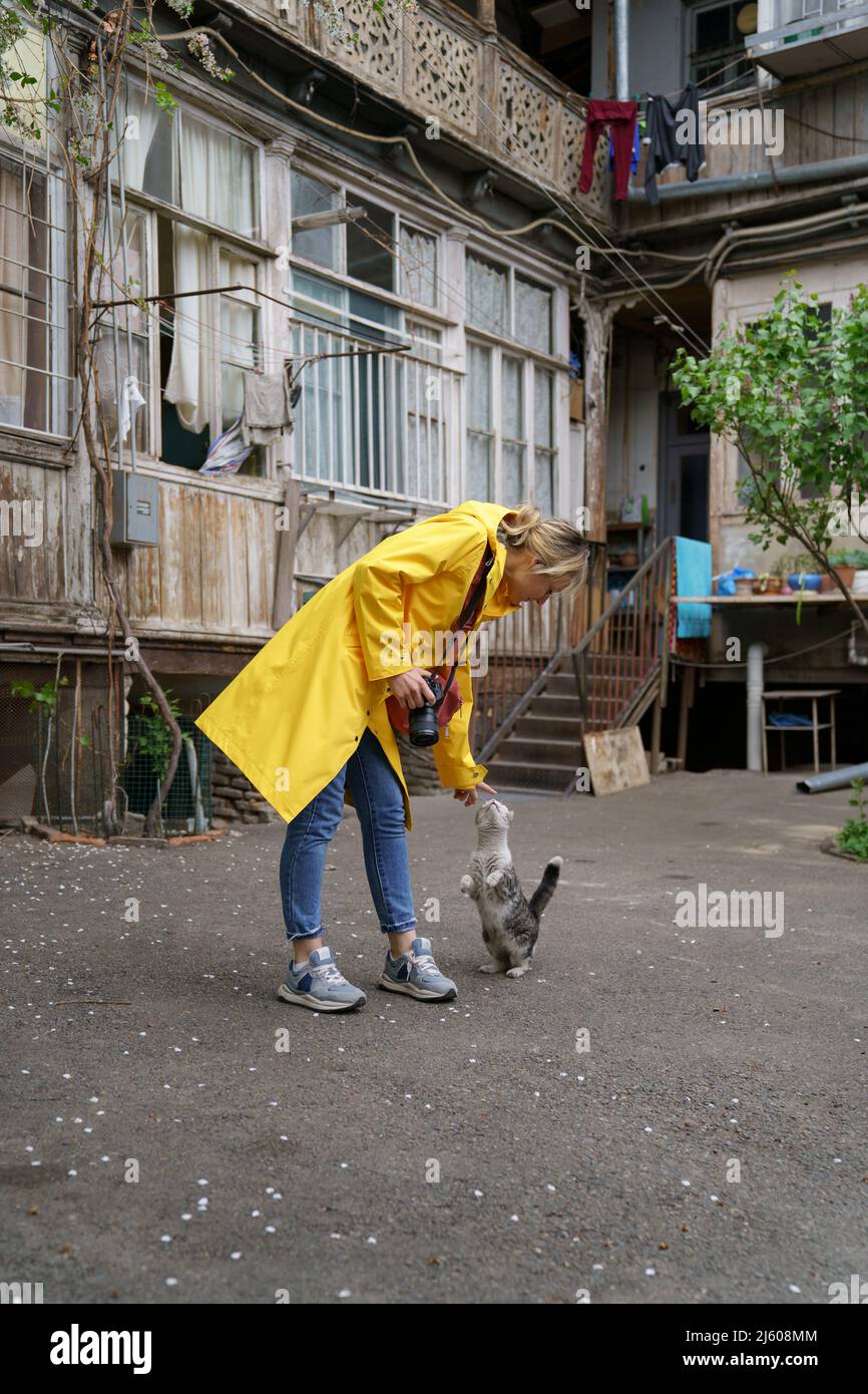 Young photographer girl playing with cat on the street in old city Stock Photo