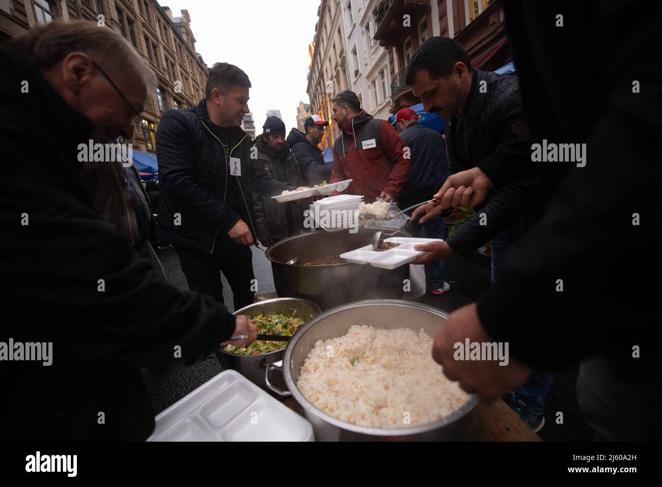 26 April 2022, Hessen, Frankfurt/Main: Employees hand out food in the Bahnhofsviertel during the 5th breaking of the fast organized by the 'Initiative gemeinsames Fastenbrechen'. In the section of Elbestraße between Münchenerstrasse and Kaiserstraße, local businesspeople and restaurants are inviting people to share a meal. The Islamic fasting month of Ramadan continues until the evening of May 1, 2022. Photo: Sebastian Gollnow/dpa Stock Photo