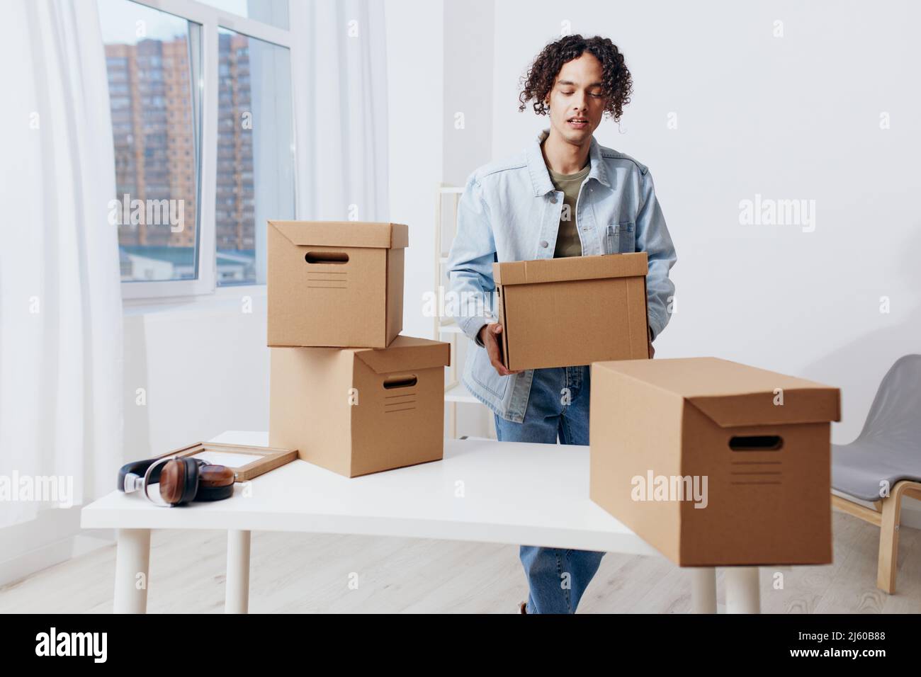 A young man unpacking things from boxes in the room Lifestyle Stock
