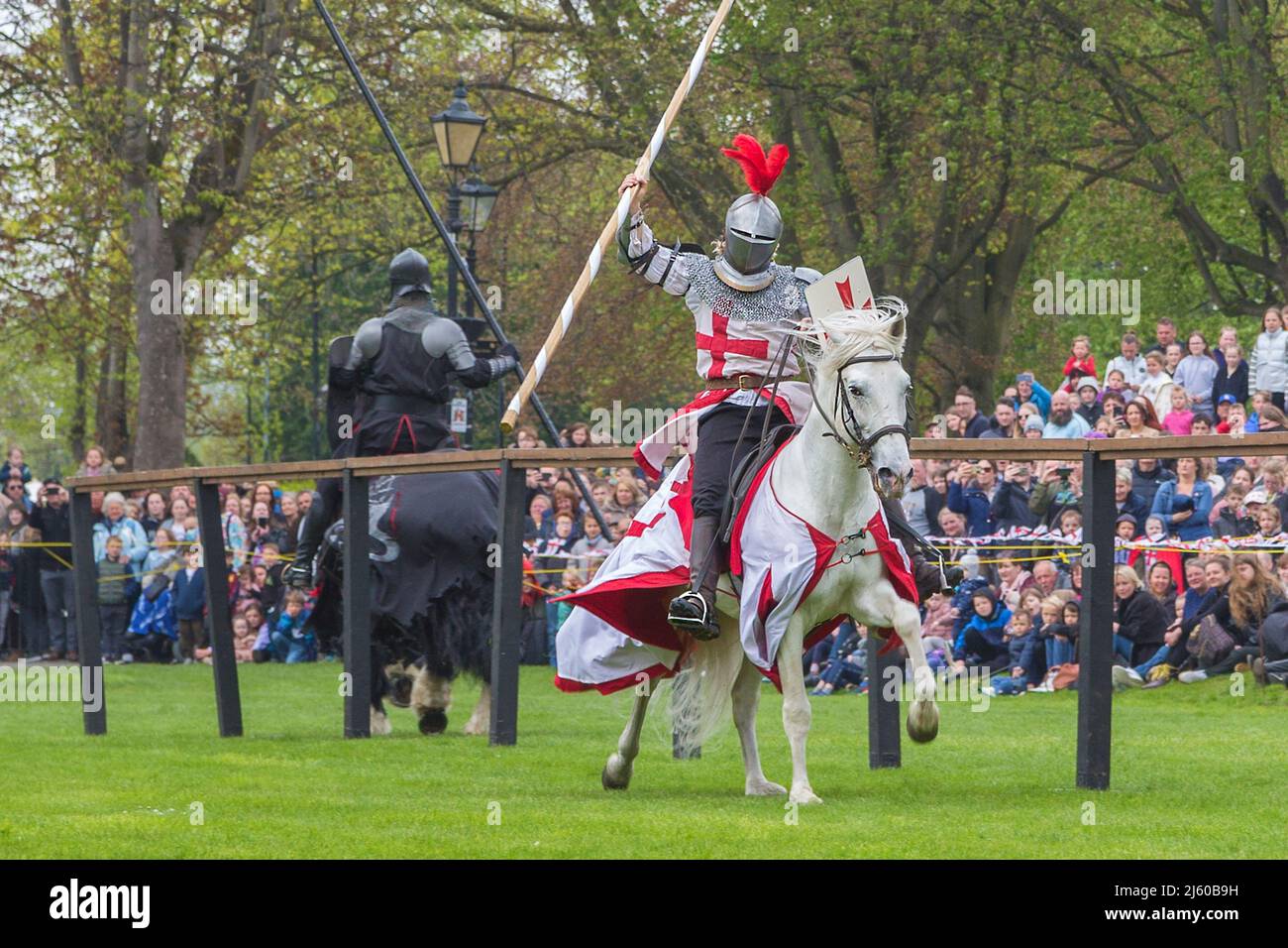 Knights on horseback joust while wearing body armour during The Grand Medieval Joust at Tamworth Castle on St. George's day. Stock Photo