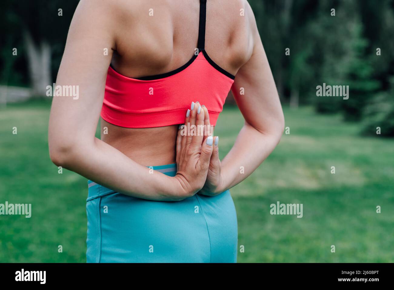 Exercises for proper posture. Body of young woman with her palms folded behind her back in Paschima Namaskarasana asana pose Stock Photo