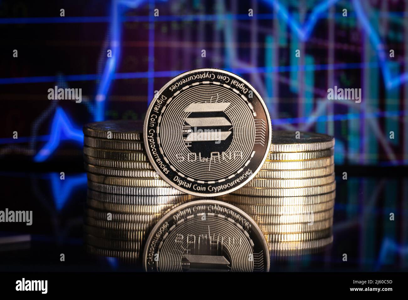 Solana SOL cryptocurrency physical coin and blurry price charts. Stock Photo