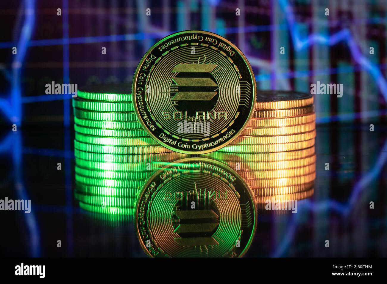 Solana SOL cryptocurrency physical coin and blurry price charts. Stock Photo
