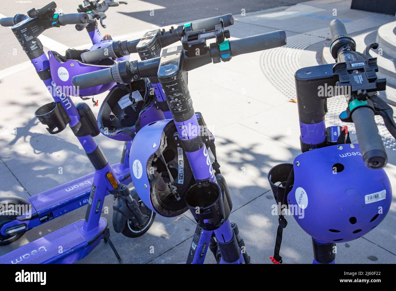 Group of Beam e scooters with helmets for hire in Canberra city centre