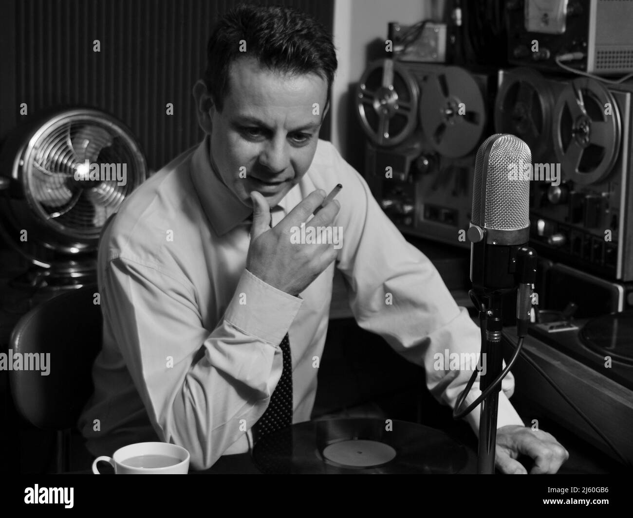 A Cool 1950's 60's Retro Radio DJ host plays music while holding record and cigarette. A classic black and white image from a bygone era. Nostalgia. Stock Photo