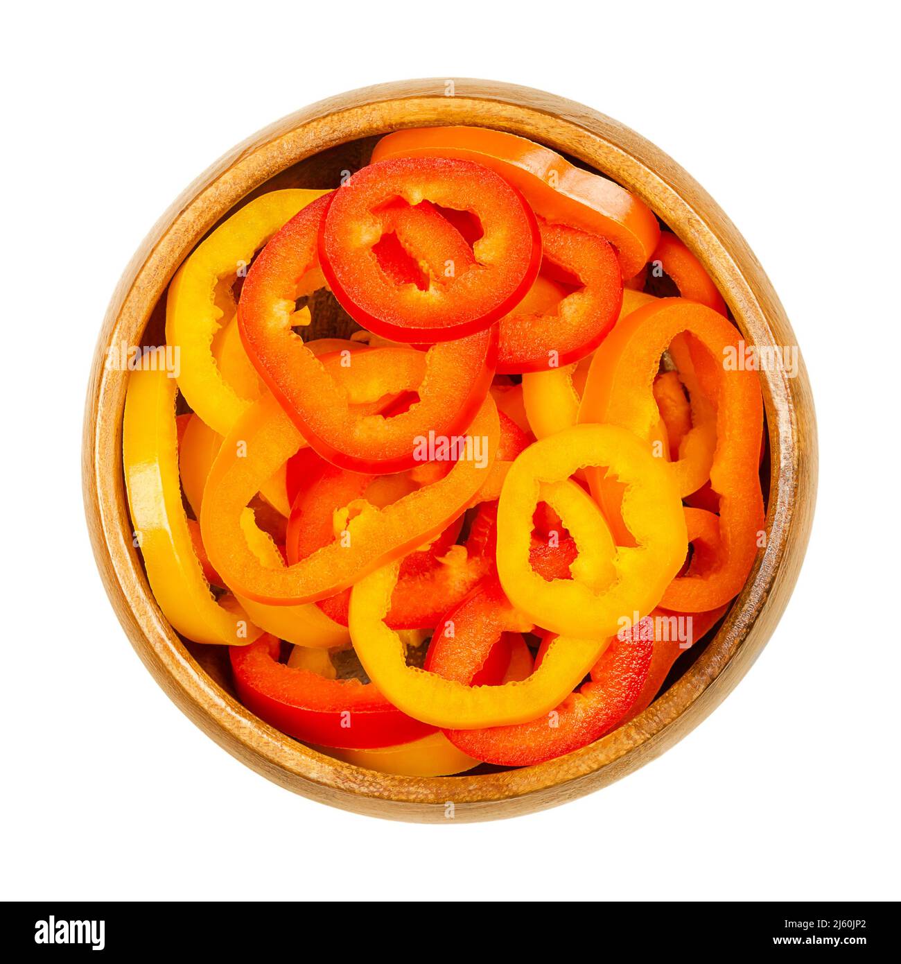 Sliced snacking mini sweet peppers, in a wooden bowl. Cross sections of ripe and fresh bell peppers, also called capsicums. Fruits of Capsicum annuum. Stock Photo