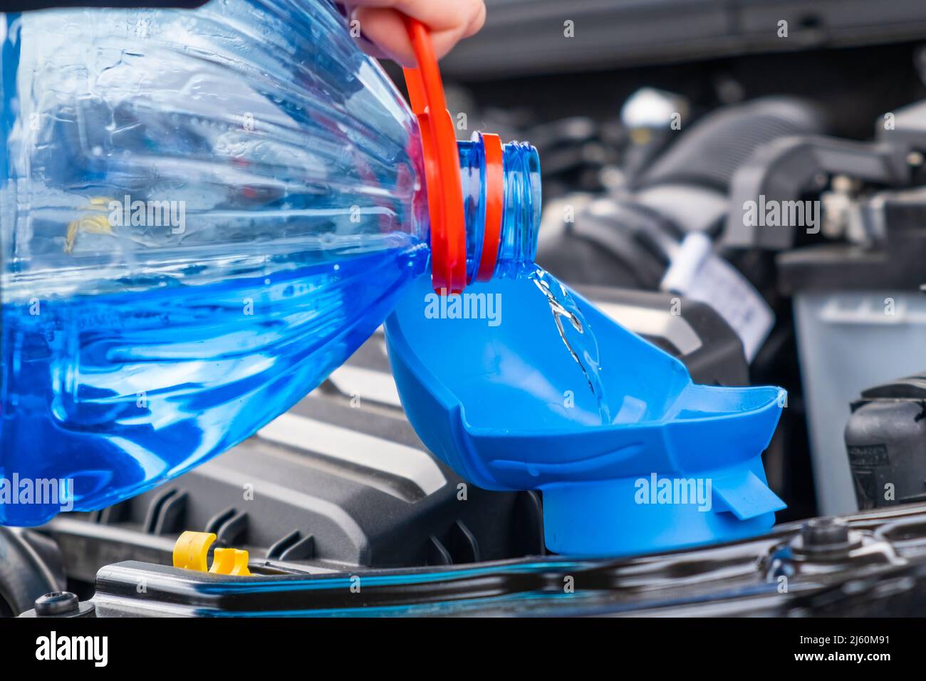 Close up driver pouring blue non freezing windshield glass washer fluid