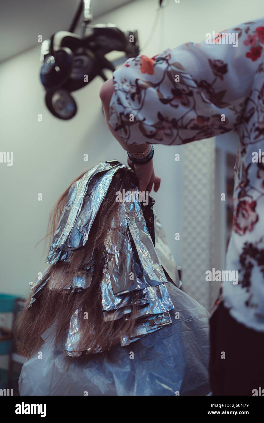 Woman dyes her hair in a barbershop, the process of dyeing her hair