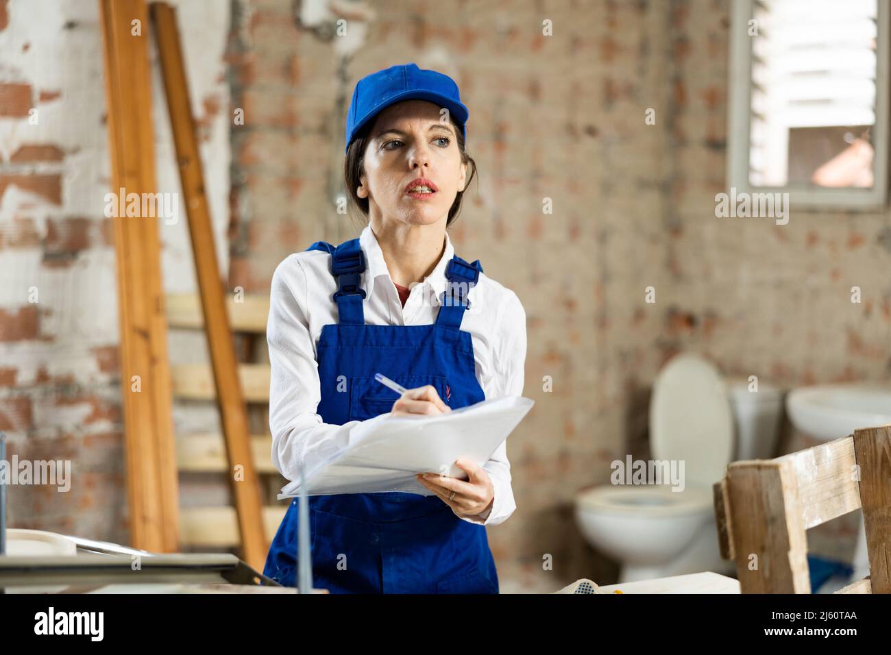 Female foreman making task list during works in building under construction Stock Photo