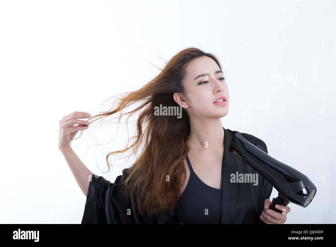 Young and beautiful Chinese woman using a hair dryer to dry hair, on white background - stock photo Stock Photo