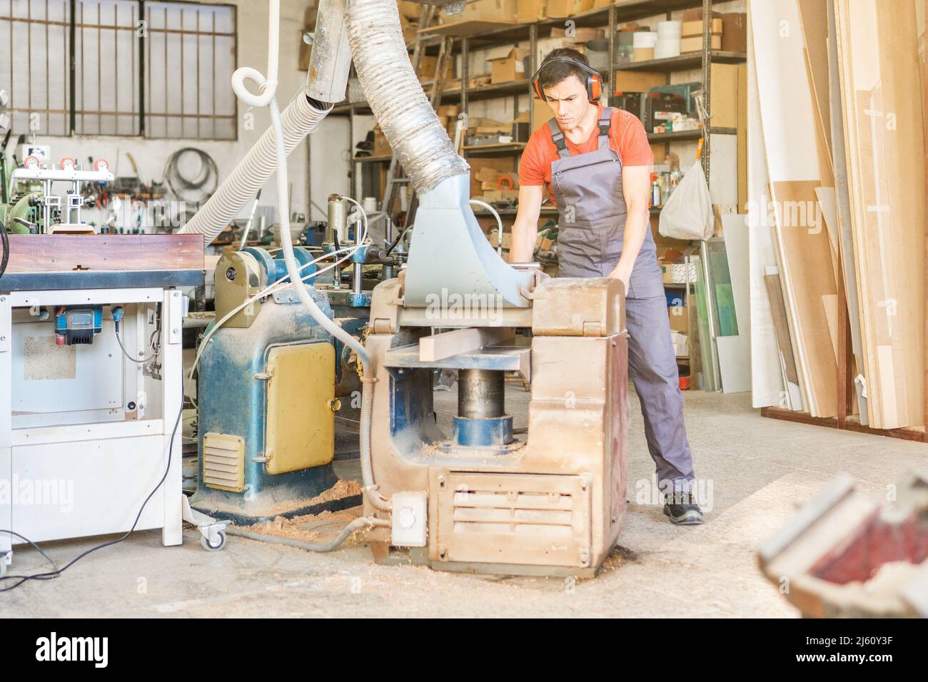 Carpenter working on thicknesser machine in joinery Stock Photo
