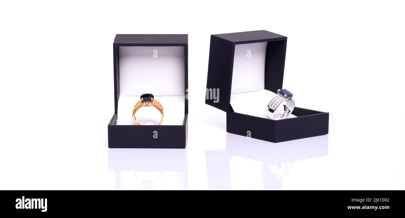 Gold ring with blue sapphire and diamond in dark blue jewel box. The platinum ring was placed next to it. Collection of natural gemstones accessories. Stock Photo