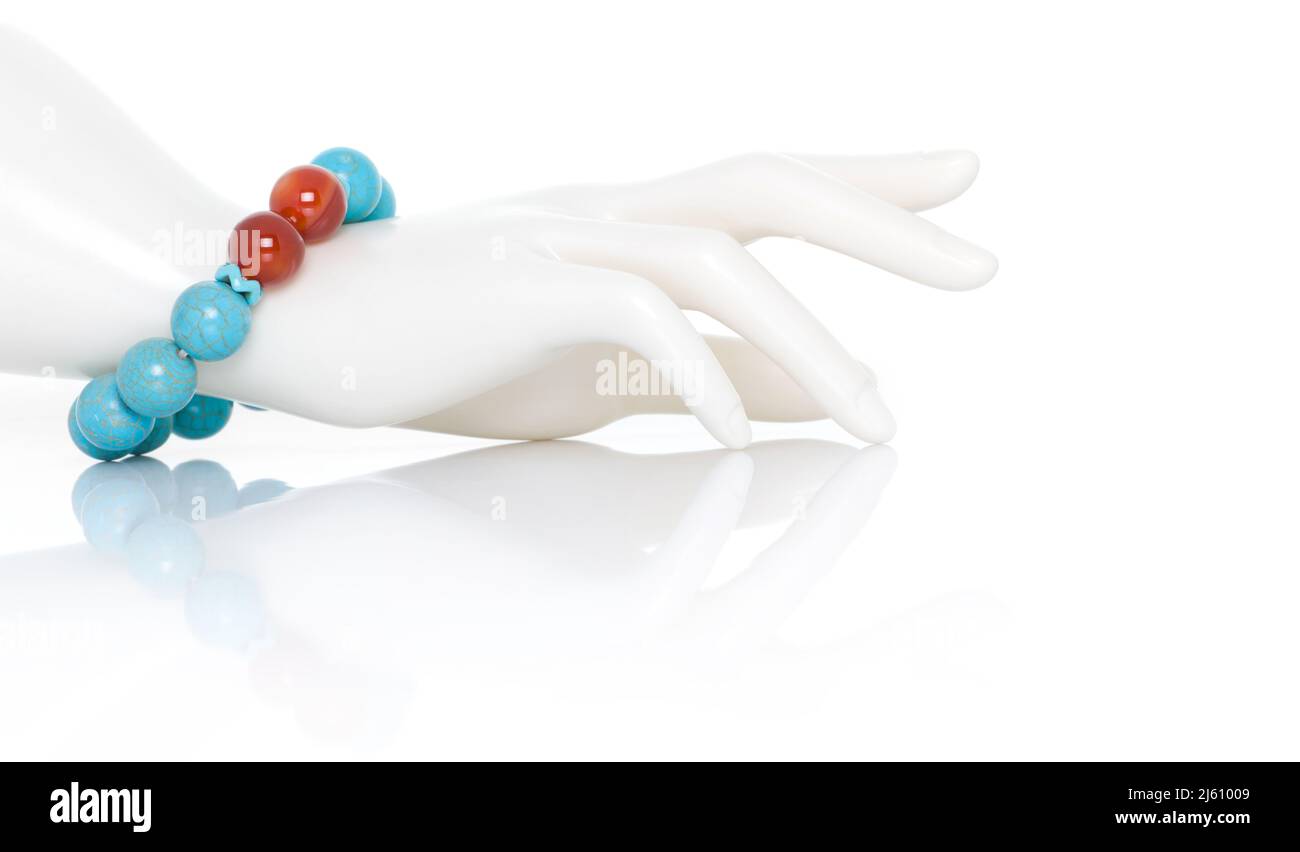 Turquoise with Carnelian Jewel or gems bracelet on plastic mannequin female hand. Collection of natural gemstones accessories. Studio shot Stock Photo
