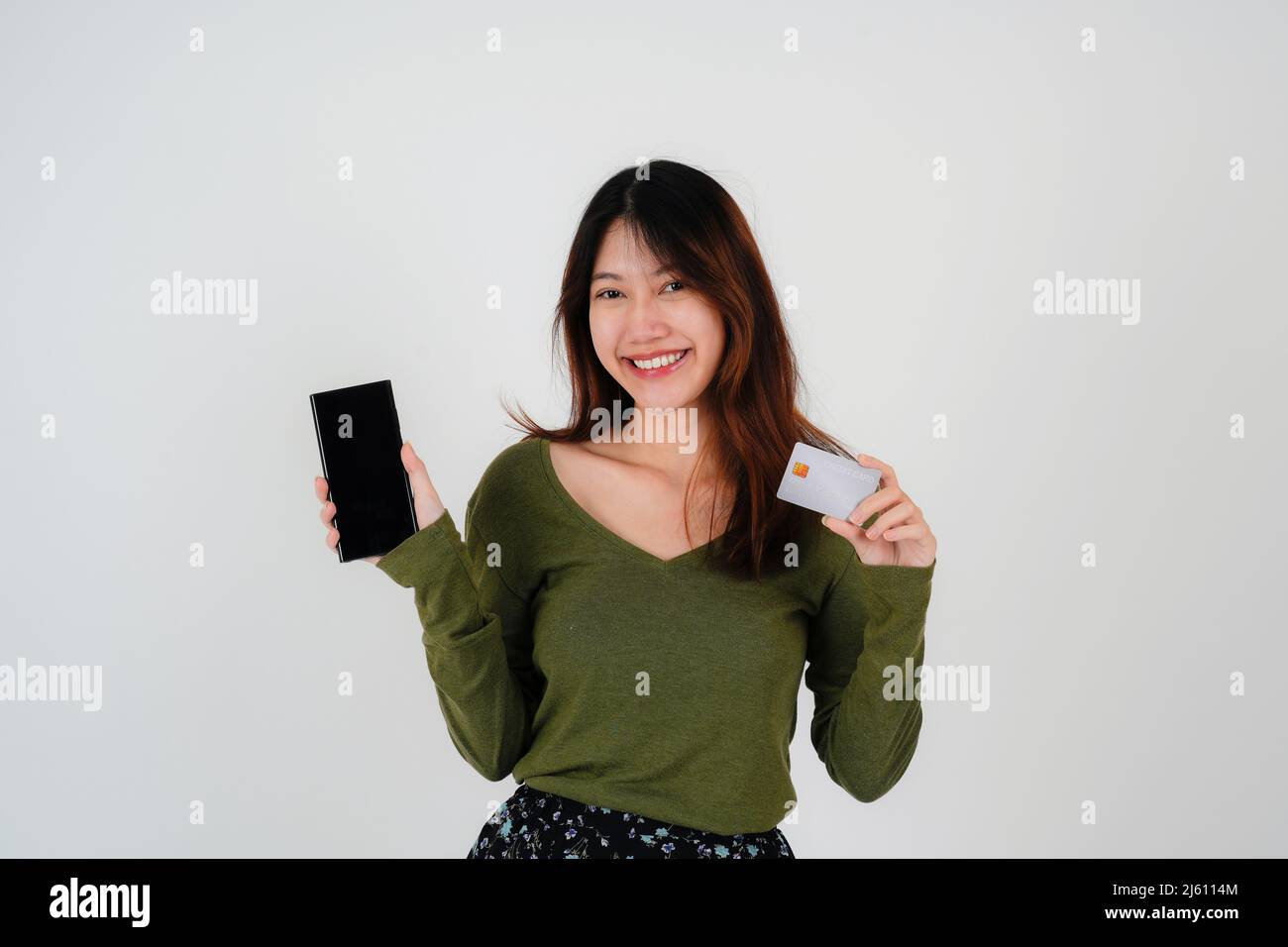 Image of a beautiful young pretty woman posing isolated over white wall background using mobile phone holding credit card. Stock Photo