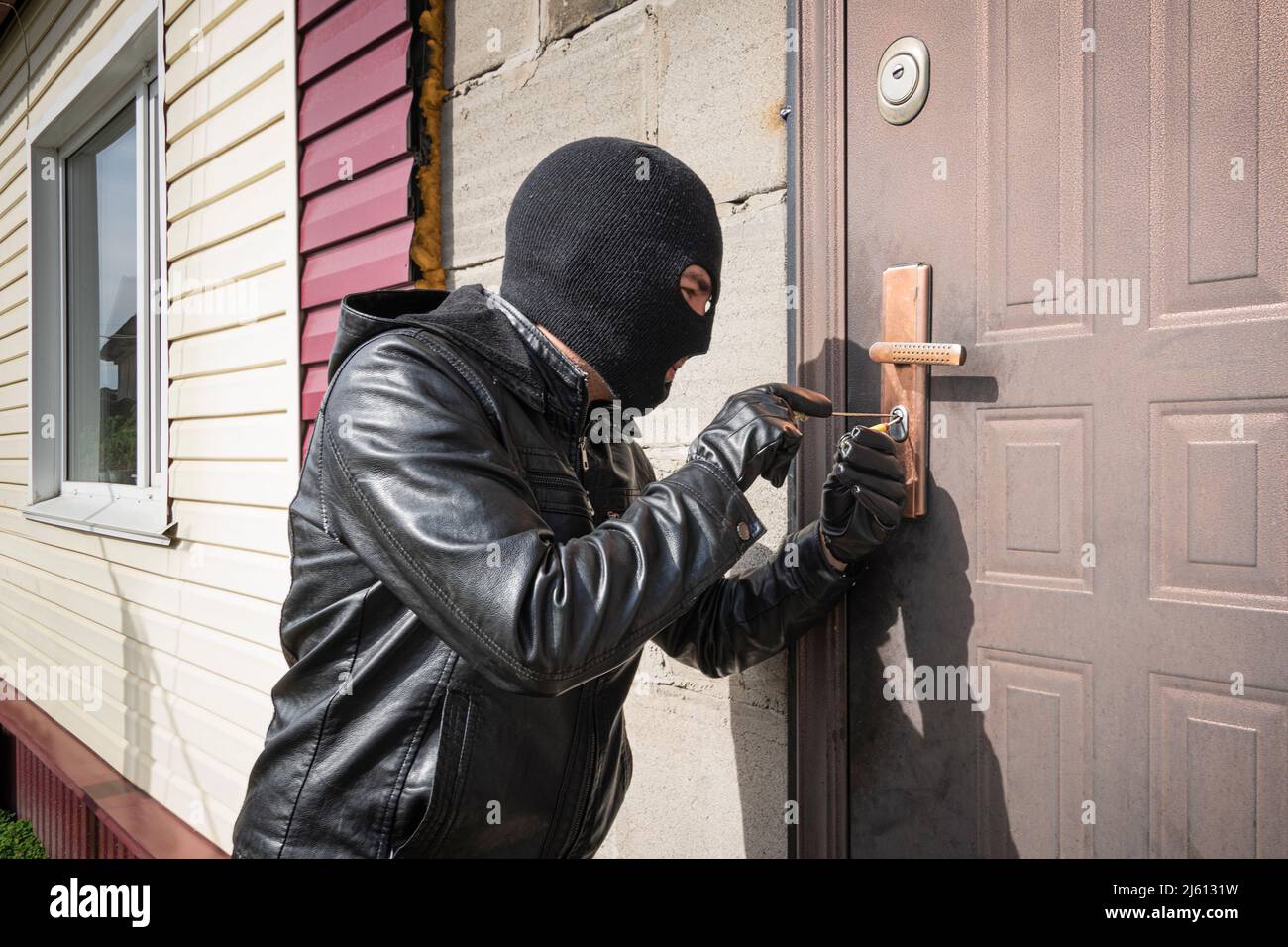 A man in a black balaclava mask opens a locked door with a lock pick. The  robber breaks into the house. Robbery of a private house. Criminal concept  Stock Photo - Alamy