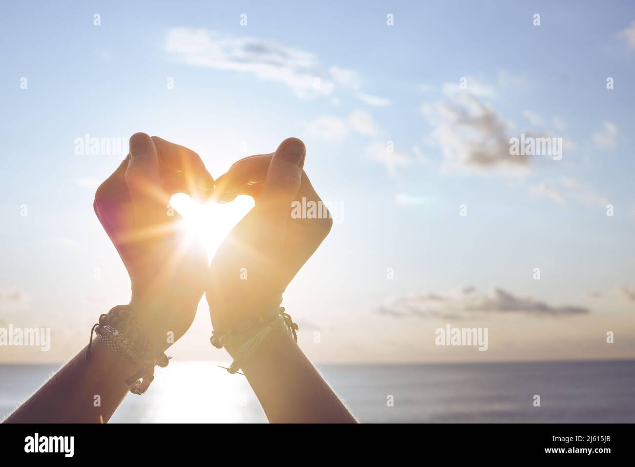 Heart shape making of hands against blue sky and sun Stock Photo - Alamy